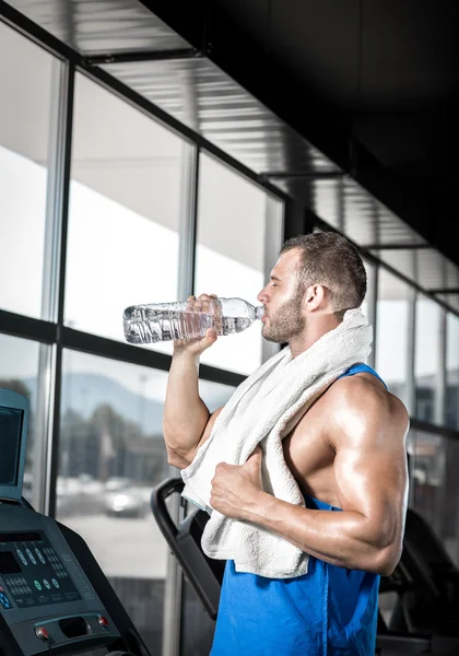 Jonge man drinkwater in de sportschool — Stockfoto