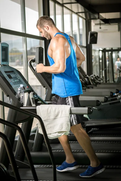 Jeune homme courant au tapis roulant dans la salle de gym — Photo