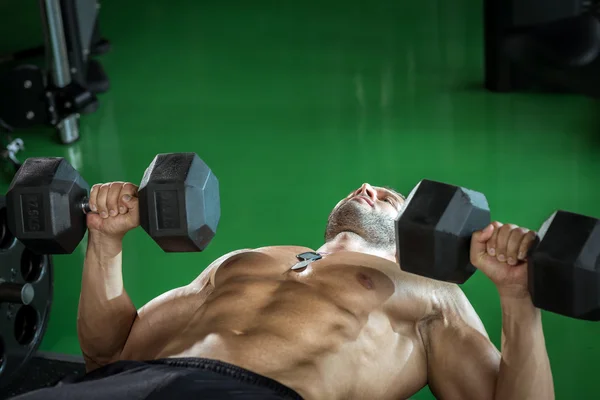 Man doing dumbbell press while lying down — Stock Photo, Image