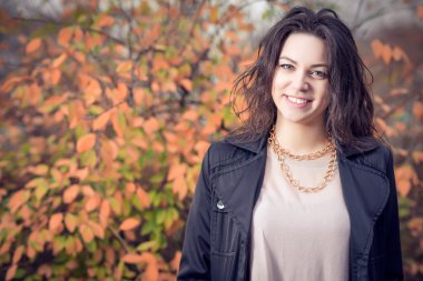 Kız parkta sonbaharda siyah paltolu.