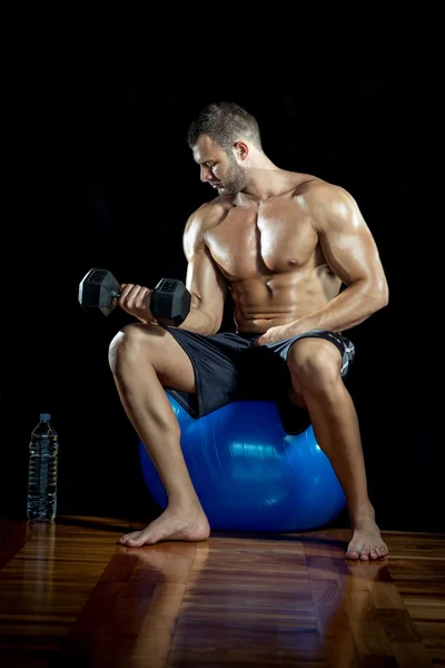 Homem fazendo cachos de bíceps na bola de fitness — Fotografia de Stock