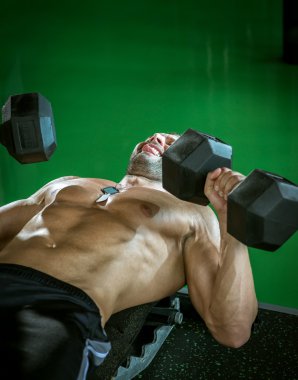 Dumbbell basın yatarken yapan erkek