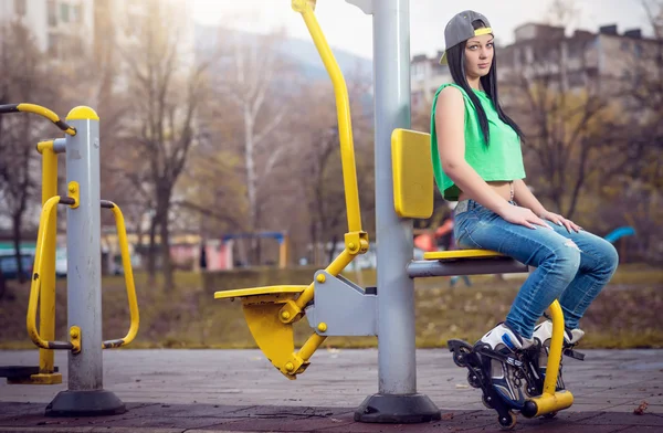 Mädchen sitzt auf Fitnessgerät mit Rollerblades — Stockfoto