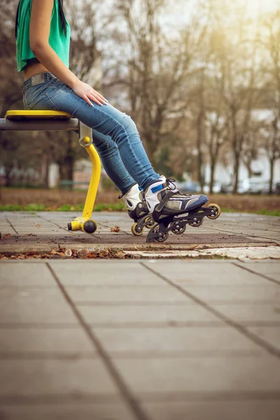 Chica sentada en la máquina de gimnasio con patines —  Fotos de Stock