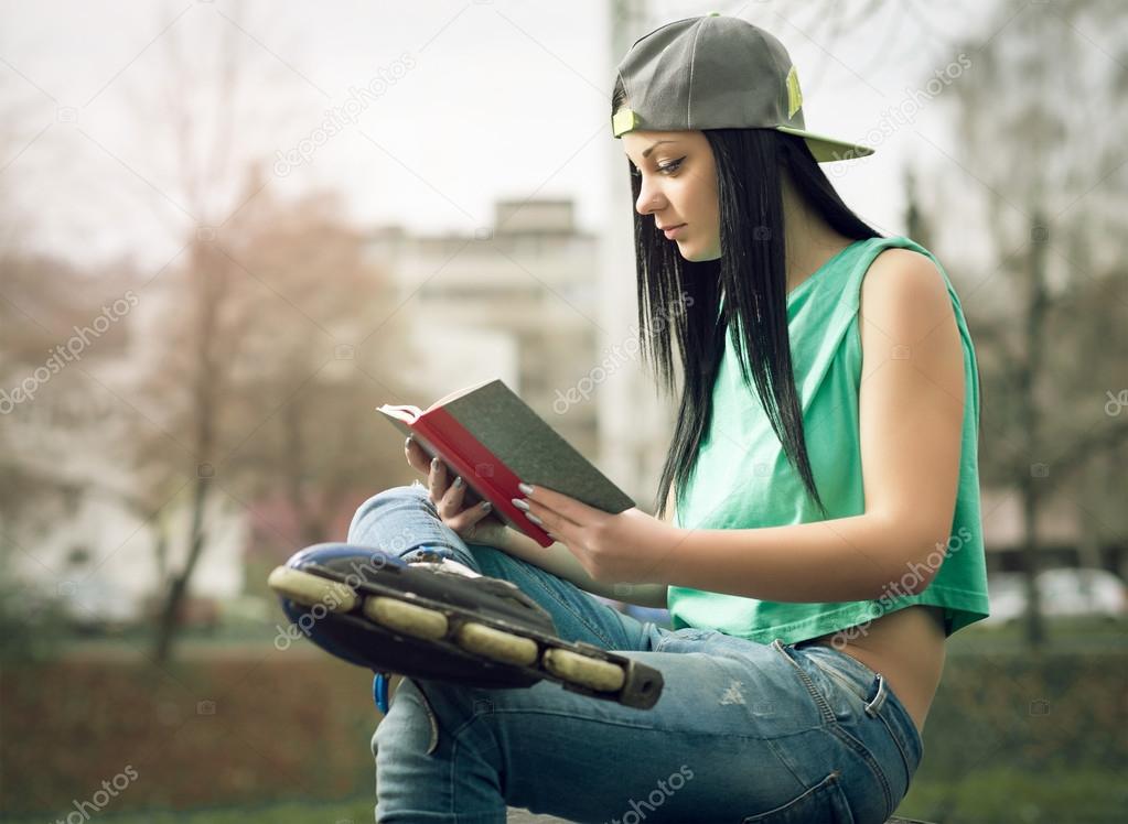 Girl in jeans reading a book on bench