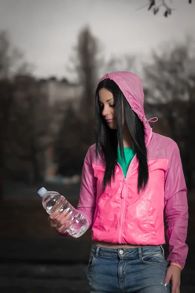 Garota segurando garrafa de água no parque — Fotografia de Stock