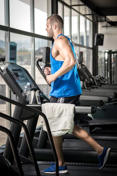 Jeune homme courant au tapis roulant dans la salle de gym — Photo