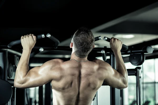 Člověk dělá pull ups v tělocvičně — Stock fotografie