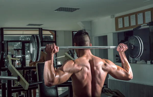 Un joven levantando pesas. Vista desde atrás . — Foto de Stock