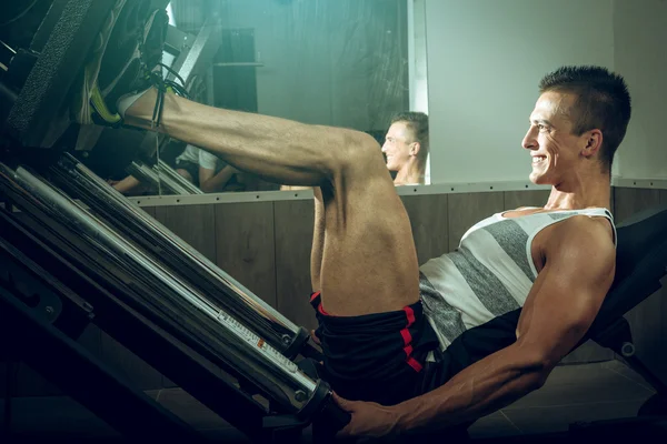 Homme utilisant la presse jambe dans la salle de gym — Photo