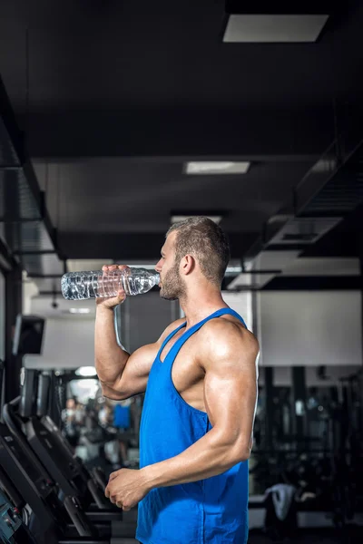 Junger Mann trinkt Wasser in Turnhalle — Stockfoto