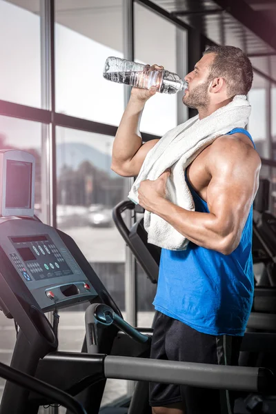 Giovane uomo che beve acqua in palestra — Foto Stock