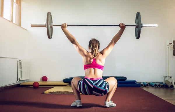 Meisje doen squats met gewicht — Stockfoto