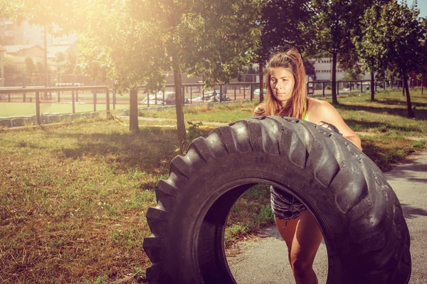 Ragazza flipping pneumatico durante l'esercizio — Foto Stock