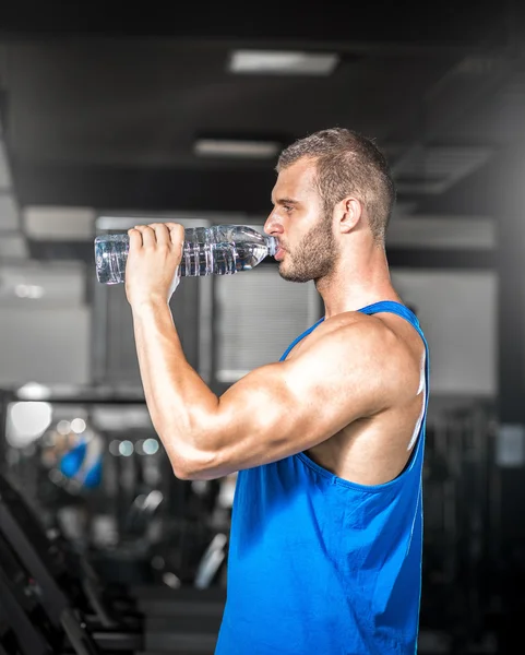 Junger Mann trinkt Wasser in Turnhalle — Stockfoto