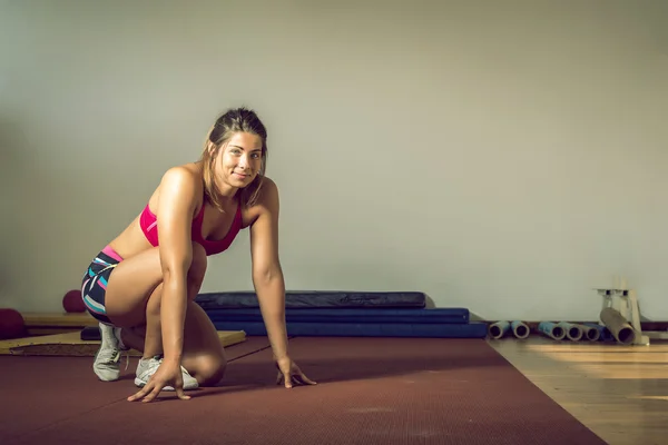 Flickan gör armhävningar i gym — Stockfoto