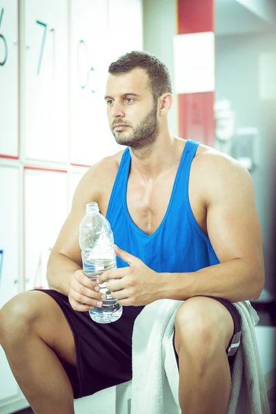 Man drinking water in locker room — Stock Photo, Image