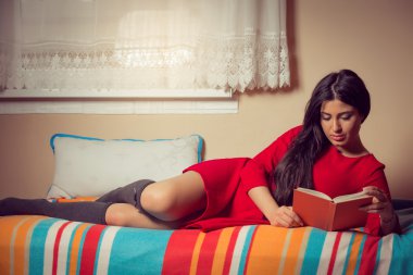 Kız yatakta yatarken ve bir kitap okuma