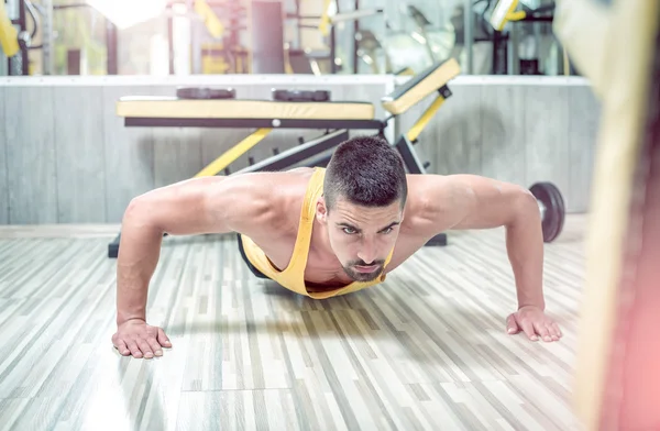 Joven haciendo flexiones en el gimnasio — Foto de Stock