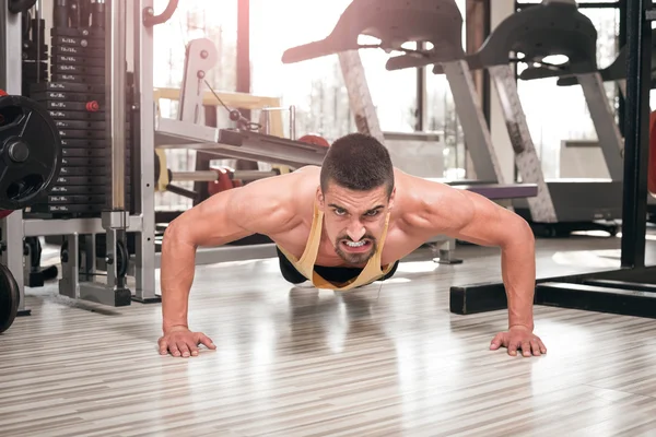 Young man doing push-ups in gym — Stock Photo, Image