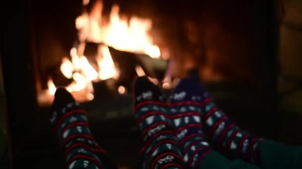 Kış mevsiminde şöminenin yanında örülmüş çorap giyen bir çiftin iki ayağı dinleniyor. — Stok video