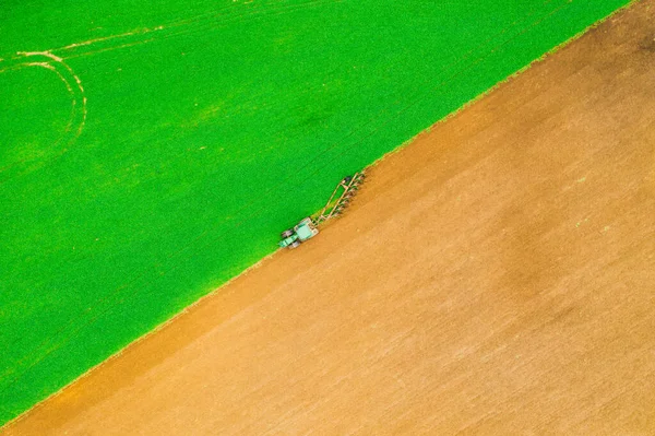 Foto aérea de campo marrón y verde. El tractor desgarra el suelo. Patrón diagonal —  Fotos de Stock