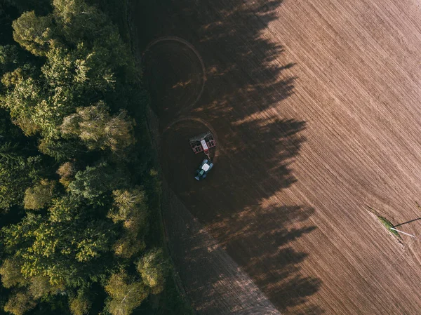 Повітряний вигляд трактора ферми на полі під час оранки землі для вирощування їжі. Візерунки на землі . — стокове фото