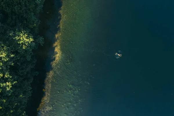 Paisaje de verano de un lago forestal. Un hombre nada solo y disfruta de un día cálido — Foto de Stock