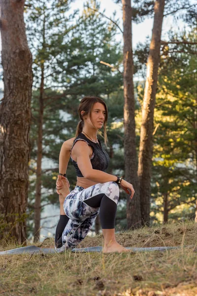 Woman practices yoga alone in the forest Back view Outdoor activity Young attractive Asian woman practicing yoga, exercising exercising working out Women is meditating alone at sunrise.