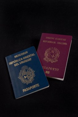 İtalyan ve Uruguay pasaportu arka planda siyah.