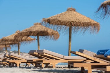 İspanya 'nın Formentera adasında güverte sandalyeleri ve saman şemsiyeleri..