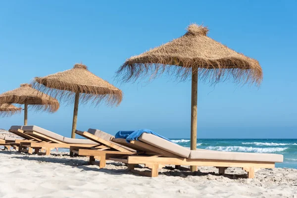 İspanya 'nın Formentera adasında güverte sandalyeleri ve saman şemsiyeleri..