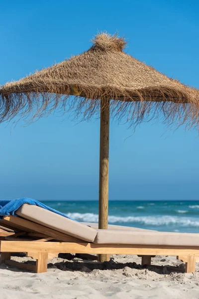 İspanya 'nın Formentera adasında güverte sandalyeleri ve saman şemsiyeleri..