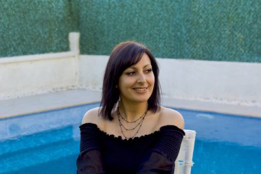 Genç bayan havuzda kameraya gülümsüyor.