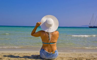 Türkiye plajında şapkalı ve bikinili bir kadın.