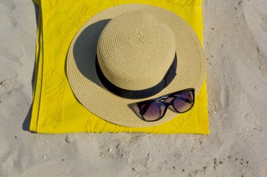  Sarı havlu, şapka ve güneş gözlüğü.