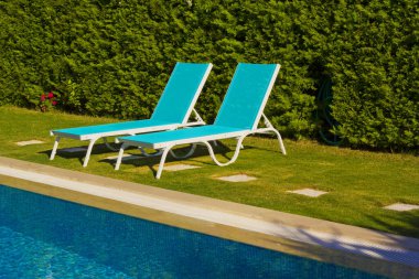 dinlenme sandalyeli bir tatil köyünde mavi yüzme havuzu.