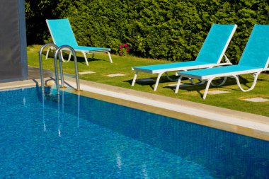 dinlenme sandalyeli bir tatil köyünde mavi yüzme havuzu.