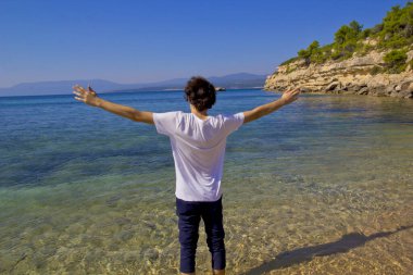  Genç bir çocuk yaz tatilinde sahilde duruyor.