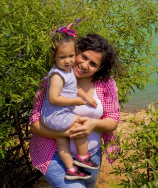 Mutlu aile yeşil doğada kameraya gülümsüyor.