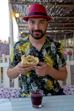 Kırmızı şapkalı genç adam balık ve ekmek yiyor.