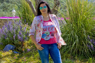 Güneş gözlüklü genç bir kadın kameraya bakıyor.