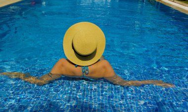 Havuzda dinlenen şapkalı genç bir kadın.