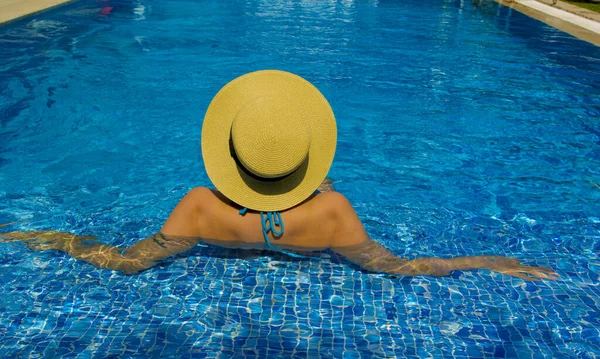 Havuzda dinlenen şapkalı genç bir kadın.