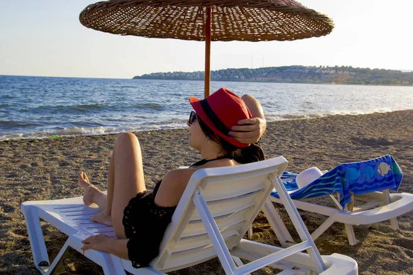 young woman in a red hat resting on the beach