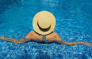 Havuzda dinlenen şapkalı genç bir kadın.