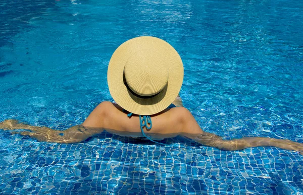 Havuzda dinlenen şapkalı genç bir kadın.