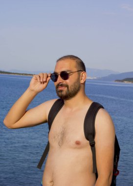 Kumsalda güneş gözlüklü mutlu genç adam.