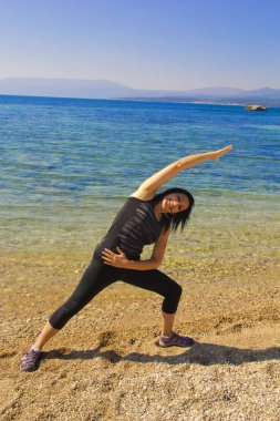 Yazın kumsalda yoga yapan bir kadın.