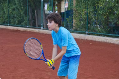 Çocuk tenis oynuyor